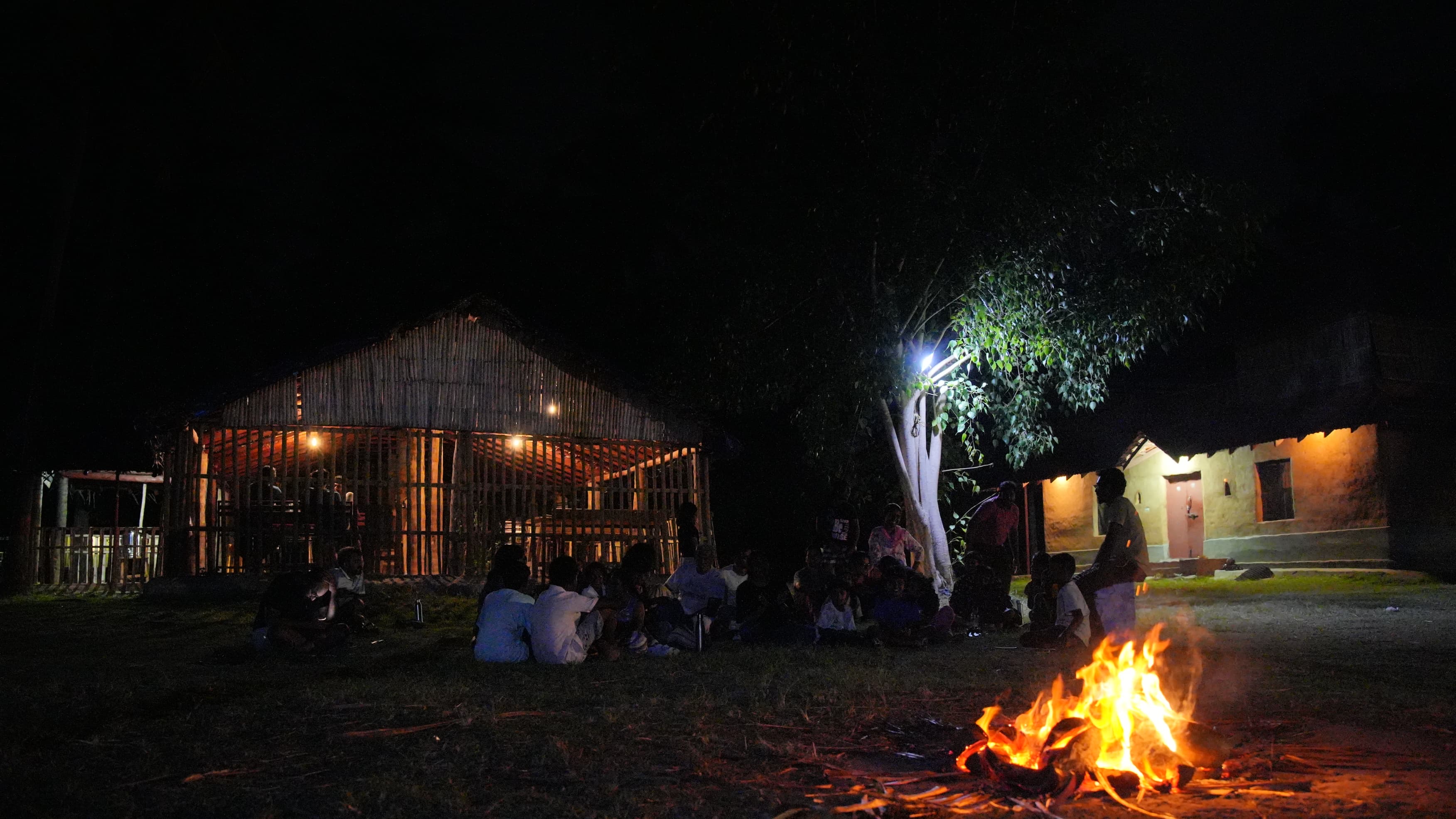Families gathered around a campfire at night at Iyal Farm