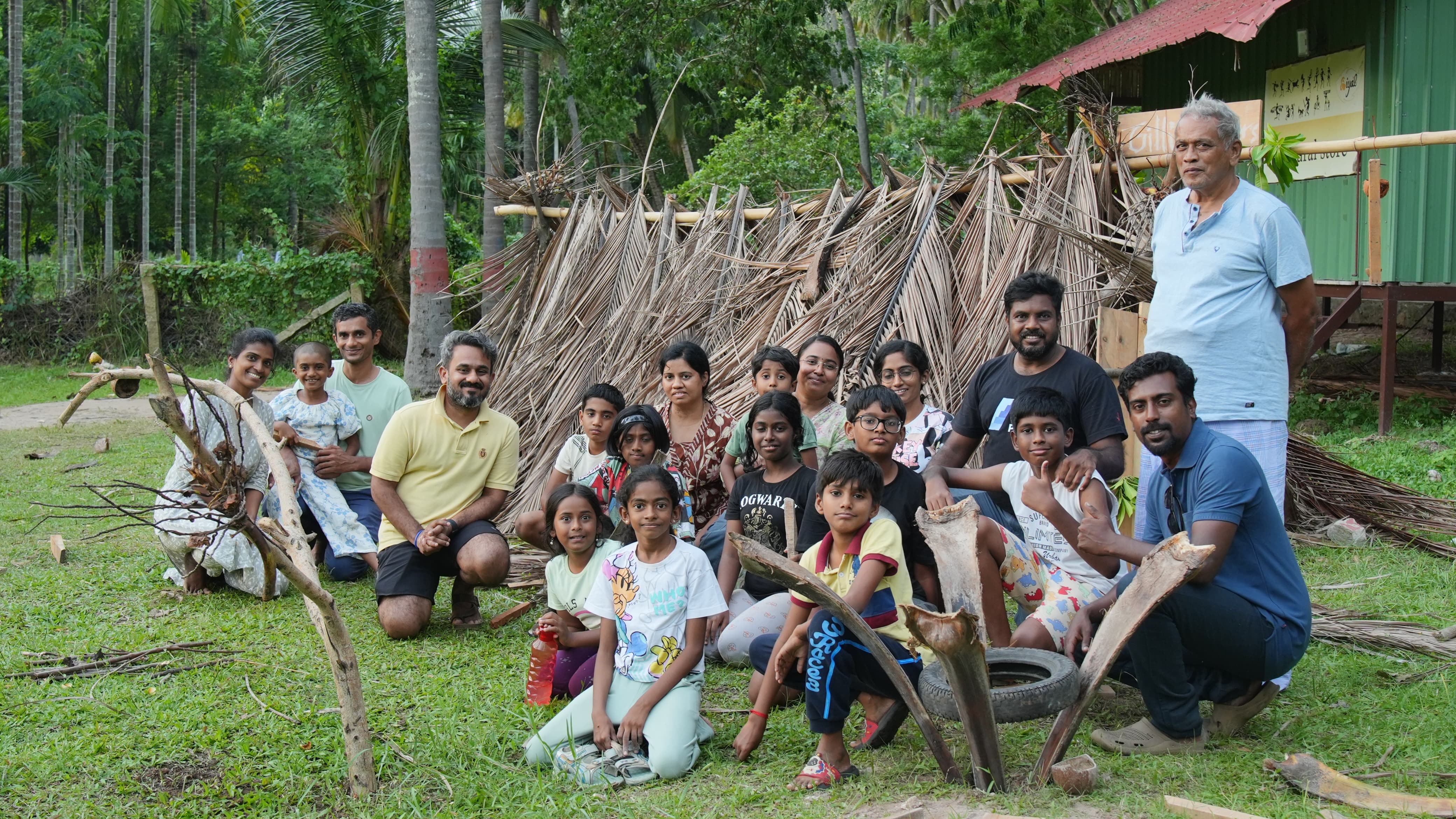 Families building a palm-leaf shelter together at Iyal Farm